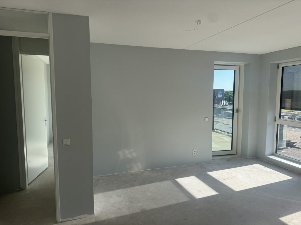 Kamer met kale lichtgrijze wanden en een betonvloer, klaar voor nieuw vlies