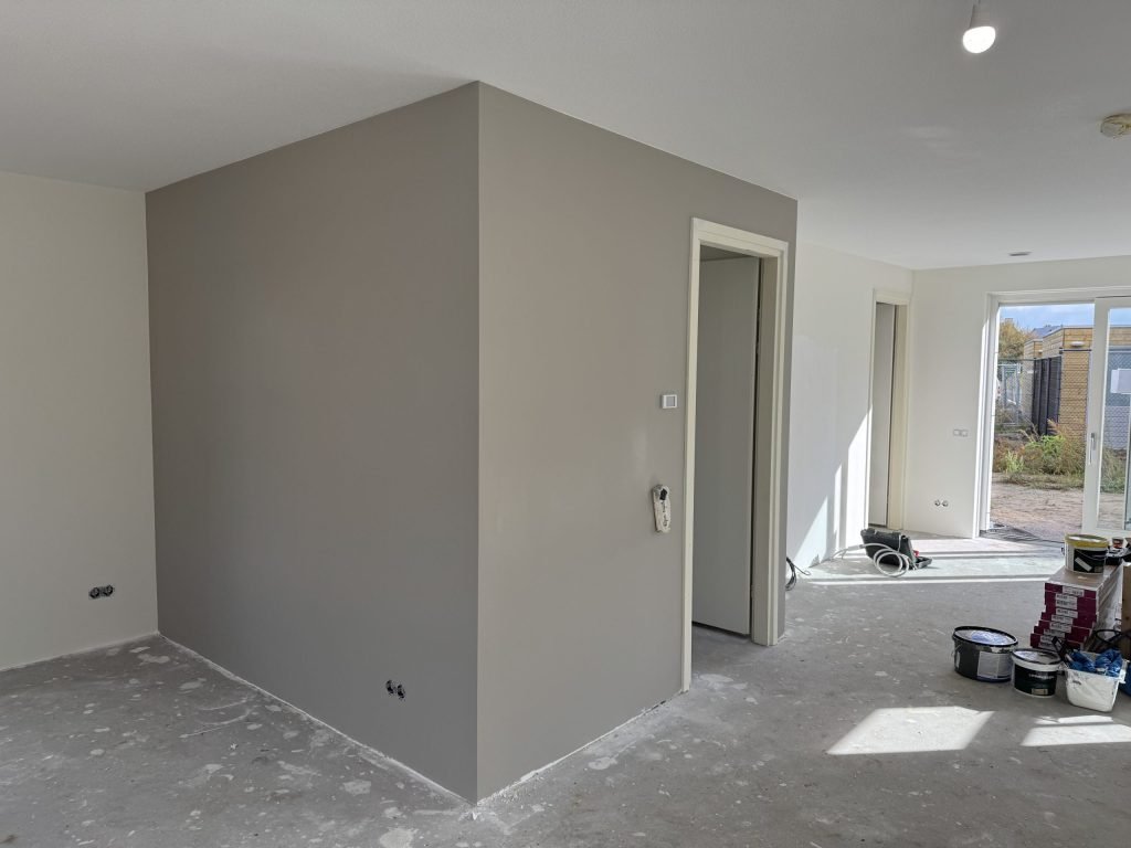 Woonruimte met een vers geverfde grijze wand en verfblikken op de vloer